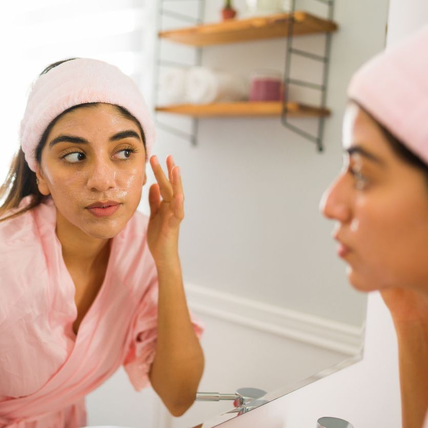 woman doing her skincare routine in mirror