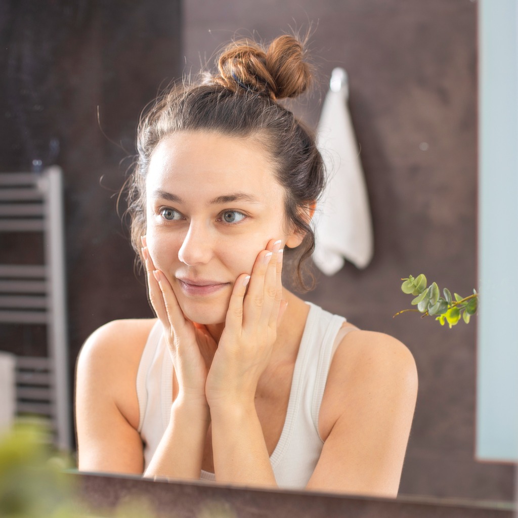 woman looking in mirror considering a professional facial