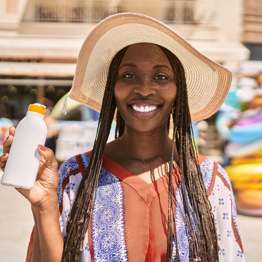 woman wearing a hat and holding sunsceen woman wearing a hat and holding sunsceen