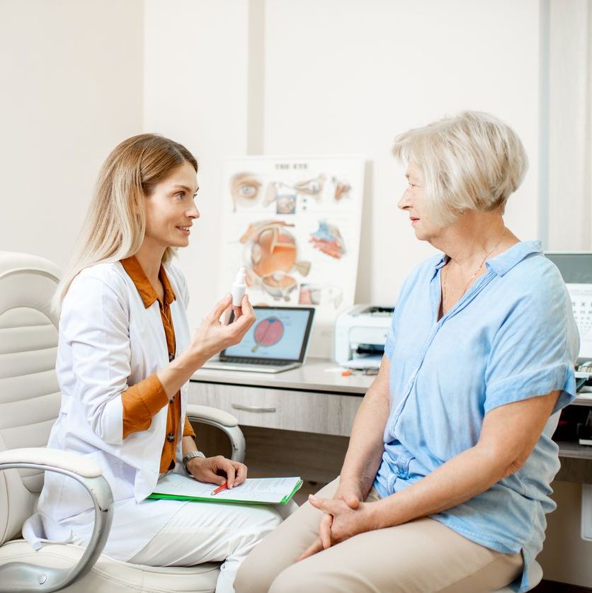 Senior woman patient talking with female ophthalmologist during a medical consultation at the ophthalmologic office. Doctor offering eye medcine for a patient